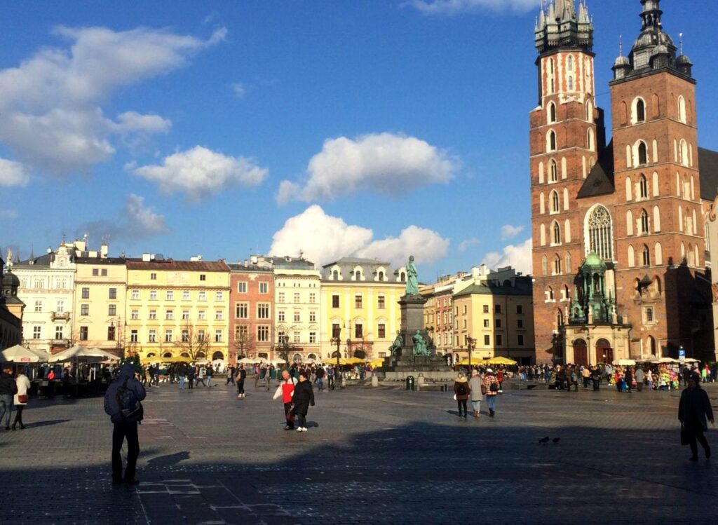 Sunny day at the Main Market Square in Krakow with St. Mary's Basilica, the perfect cultural finale to your active holidays after exploring what to do in Slovakia.